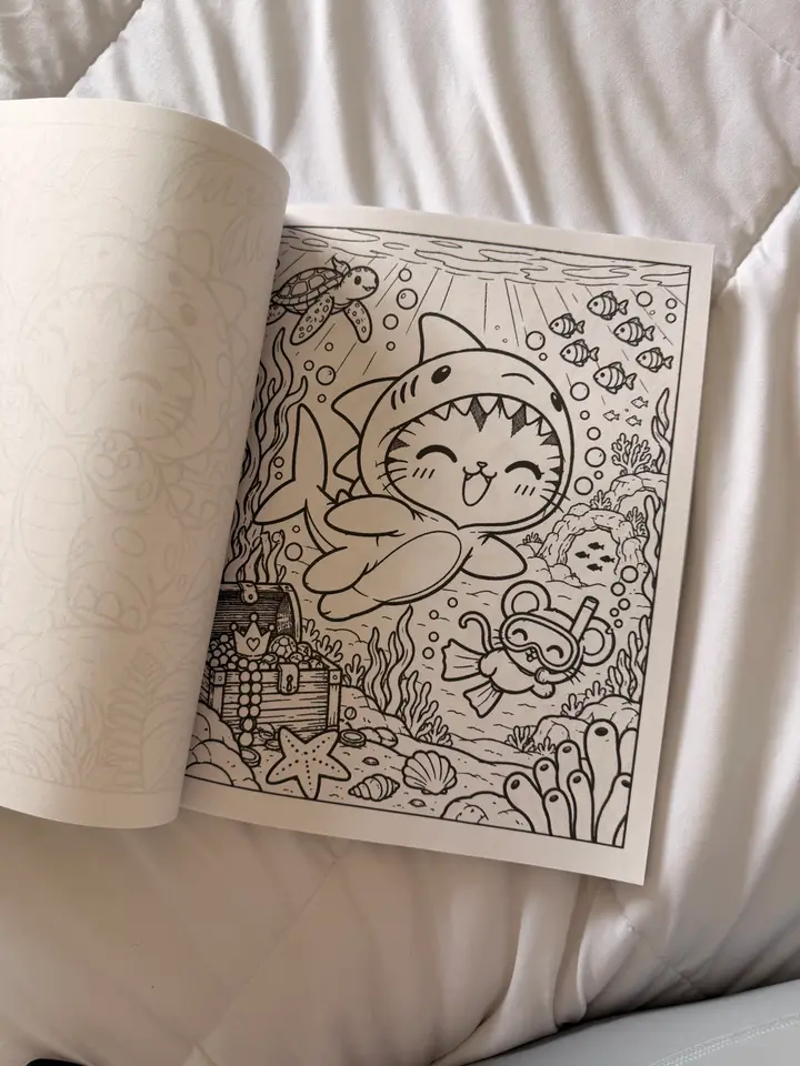 A photo of a printed coloring page showing Sassy in a shark costume and Squeak snorkeling underwater.